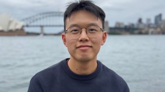 Nathan Wang-Ly stands in front of the Sydney Harbour Bridge and Opera House.