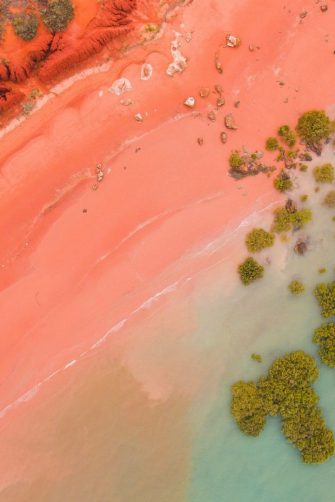 Roebuck bay in broome, western australia as seen from the air. SHowing the pink beach, red cliffs, turquoise water and green mangroves. 