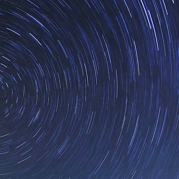 Sky with a trail of stars revolving on the polar star indicating where north is on a lake.