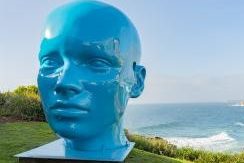 A blue head sculpture set overlooking the sea