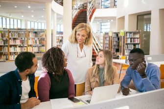 Students and teacher discussing work in library