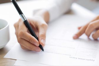 Image of person writing on a form