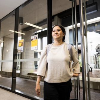 Student smiling in front of door of Student Services