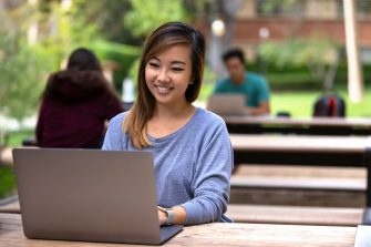 Attractive female asian american cheerful, working remotely from laptop computer at park