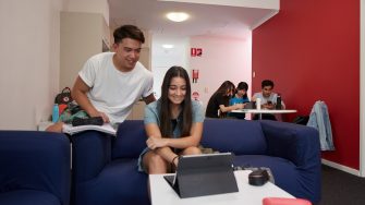 Group of students studying at table and on couch in accommodation common room