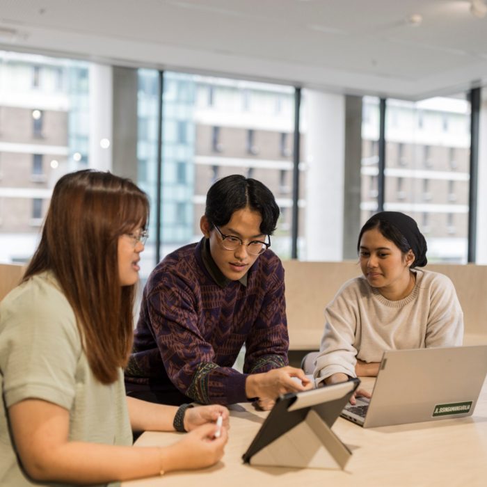 Three students studying with laptops in the Student Hub at L5 at desk