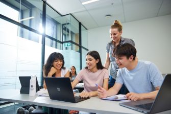 UNSW College Students in classroom, working on laptops, teacher supervises and educates