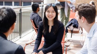 three students siting in the UNSW campus and talking to each other