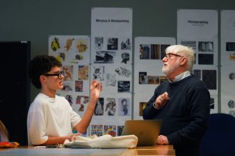 Diversified staff talking with students in classroom