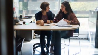 Counselling appointment for young asian woman student in counsellor College office. Horizontal indoors backlit full length shot with copy space.