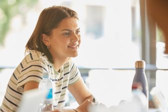 A female student looks content while listening to conversation  in warm sunlight