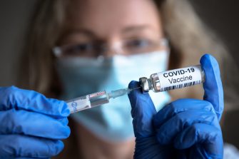 COVID-19 vaccine in researcher hands, female doctor holds syringe and bottle with vaccine for coronavirus cure. Concept of corona virus treatment, injection, shot and clinical trial during pandemic.