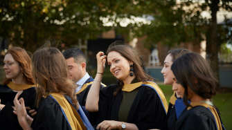 Students smile as they stand together in graduation gowns