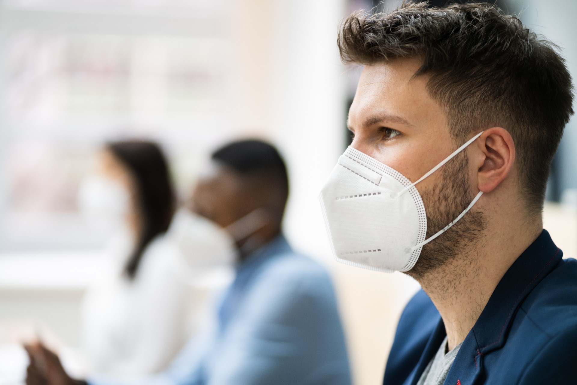 Three young people each wearing a face mask in the office
