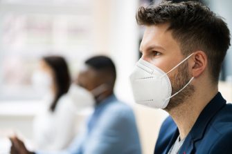 Three young people each wearing a face mask in the office