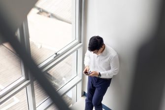Handsome office worker hold mobile phone in hand chat with girlfriend by mobile phone at modren office balcony in relax time.