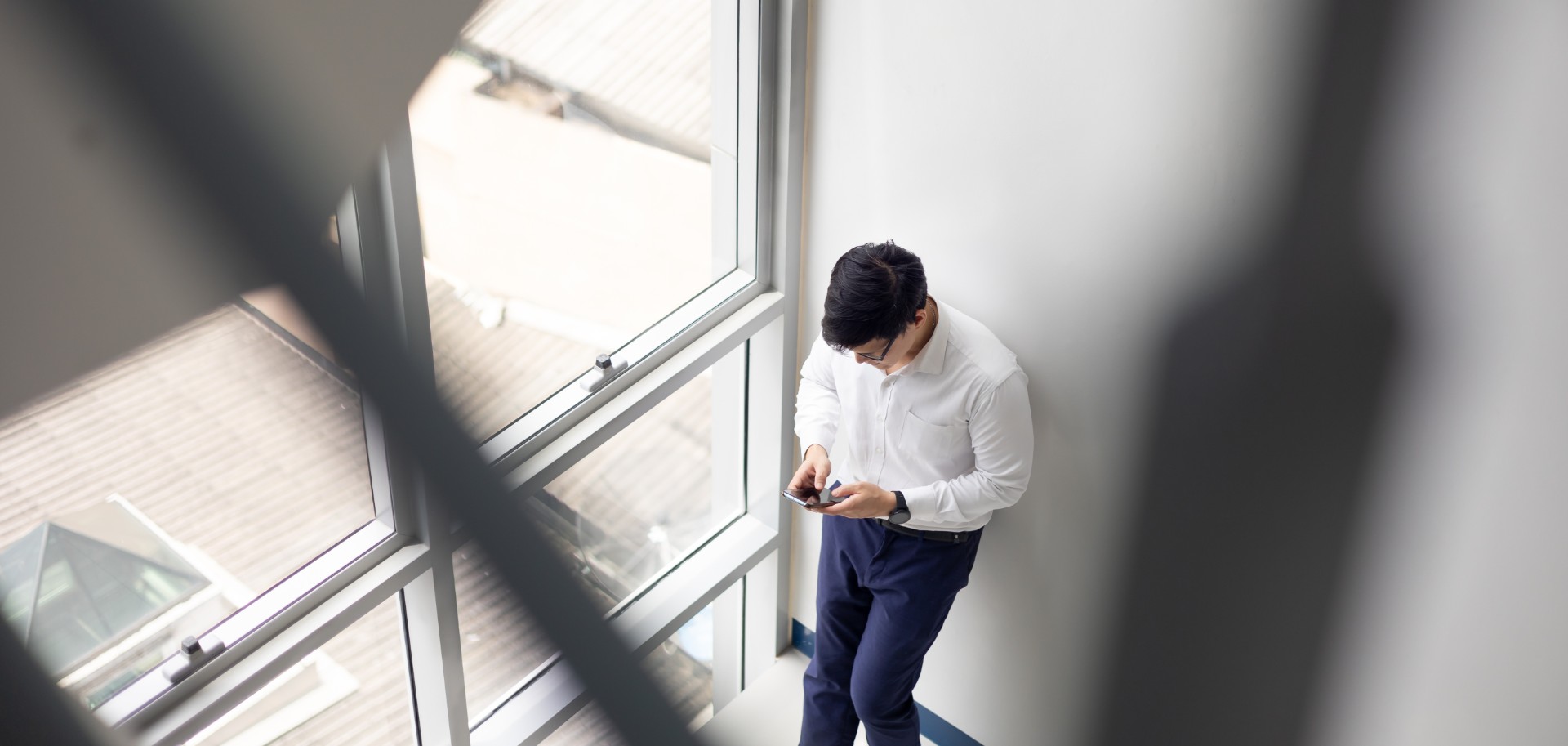 Handsome office worker hold mobile phone in hand chat with girlfriend by mobile phone at modren office balcony in relax time.