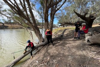 Four people are standing next to a river near Walgett