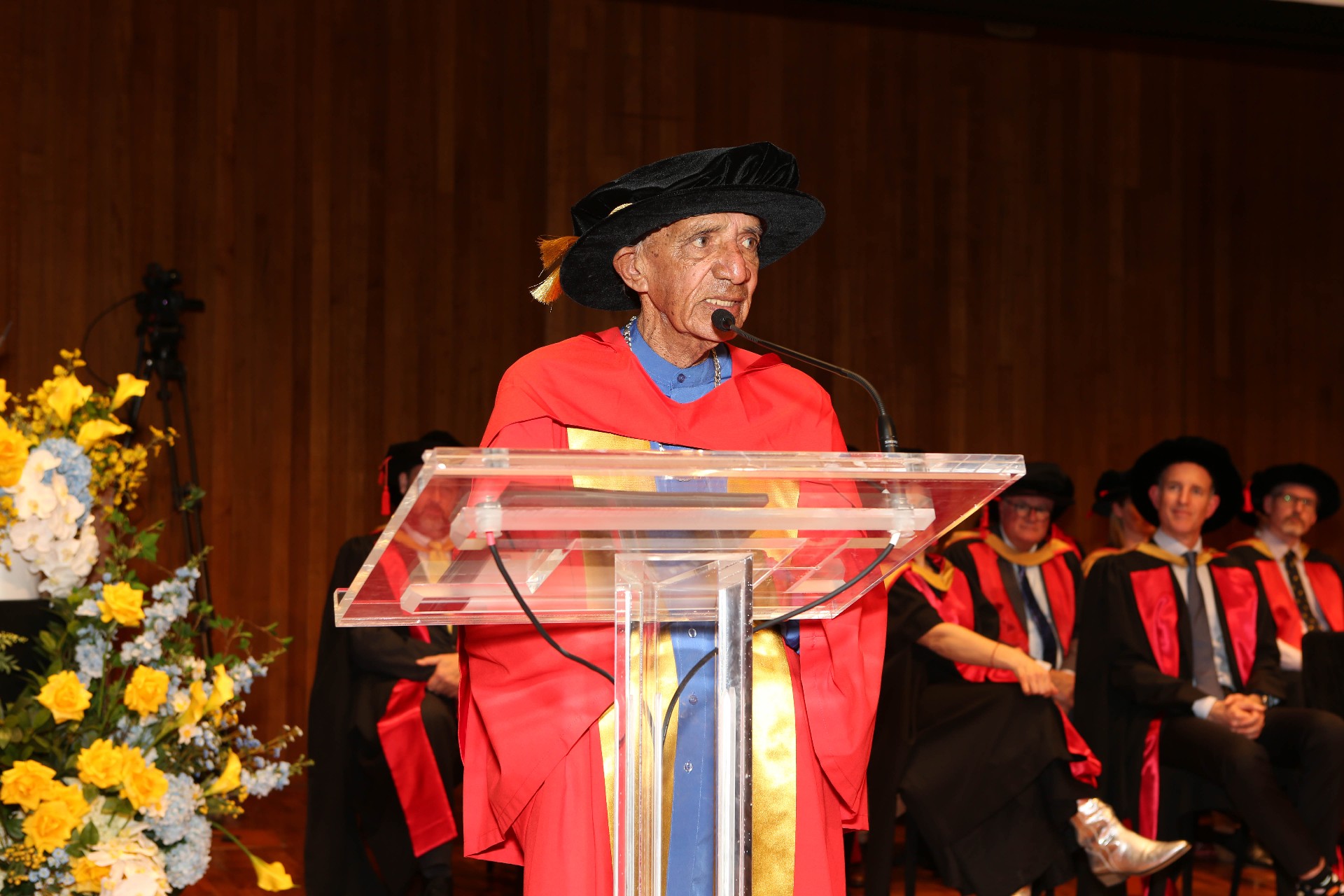 Indigenous man Uncle Vic standing at the podium of a graduation ceremony.