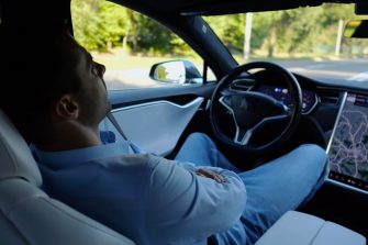 Male businessperson experience to ride an autonomous self driving electric car at urban road. Confident businessman resting during riding on electrical auto with autopilot at city. Slow mo