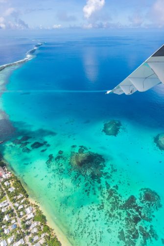 Tuvalu under the wing of an airplane. Aerial view of Funafuti atoll and the airstrip of International airport in Vaiaku. Fongafale motu. Island nation in Polynesia, South Pacific Ocean, Oceania.