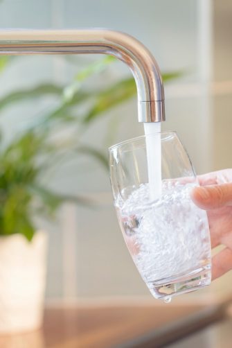 Filling up a glass with clean drinking water from kitchen faucet