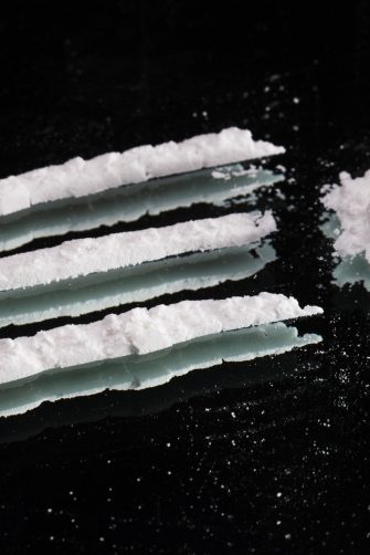 Cocaine drugs heap and lines still life on a dark mirror, close up view