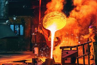 Liquid iron molten metal pouring in container, industrial metallurgical factory, foundry cast, heavy industry background.