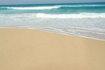 Dangerous current sign for swimmers at the beach in Australia. Lonely surfer entering the water on the background