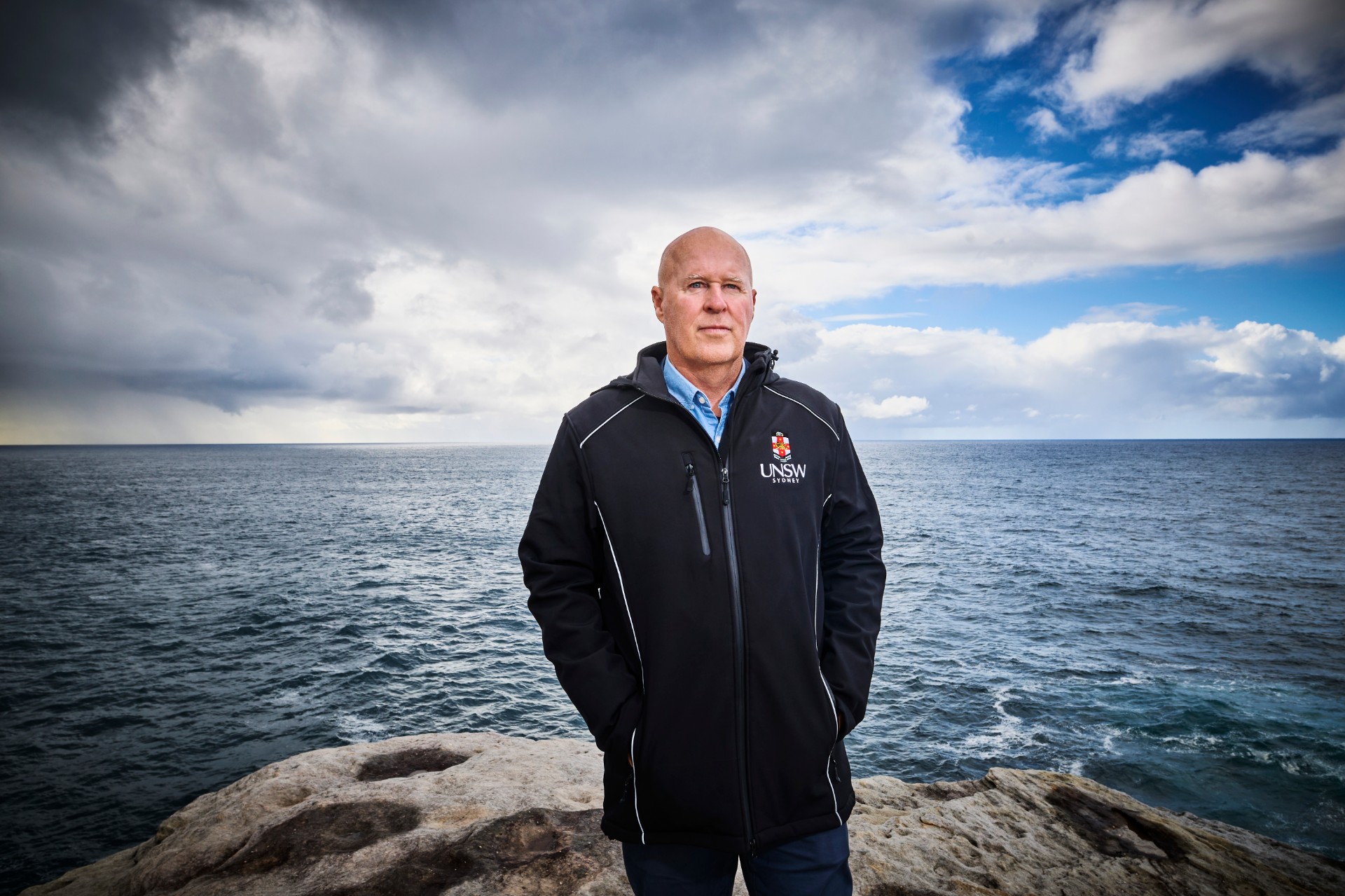 Photo of Professor Matthew England standing on a clifftop with the ocean in the background
