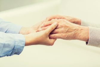 close up of senior and young woman holding hands