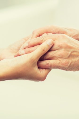 close up of senior and young woman holding hands