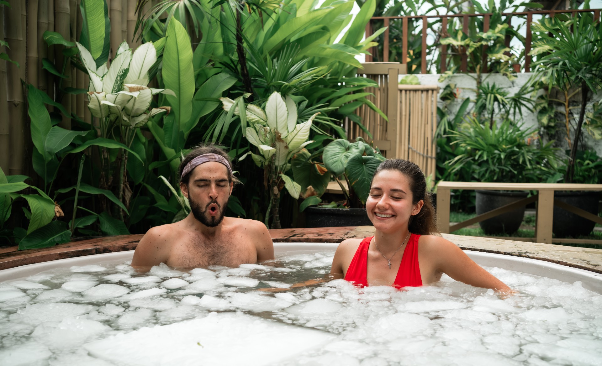 Man and woman take an ice bath outdoors in a tropical setting. Cold plunge for health, recovery, and resilience. A trending wellness practice combining nature, biohacking, and therapy