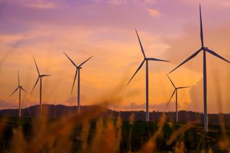 Wind turbines produce electricity and sunlight during sunset.