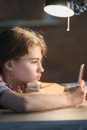 Teenage girl with mobile phone late in evening