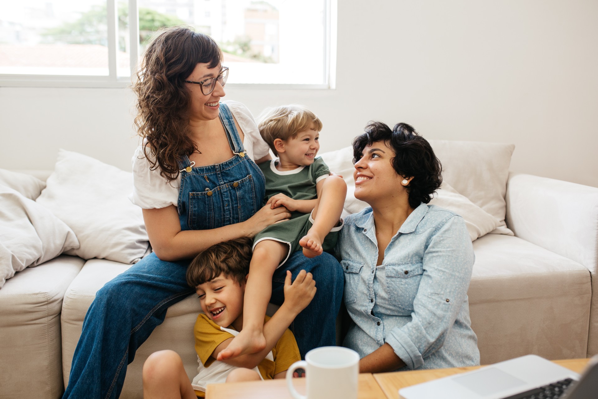 Happy lesbian couple playing with their children at home. Beautiful family of four having great time together indoors.