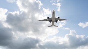 jet airplane flying, traveling in the sky overhead from below the underside of the plane
