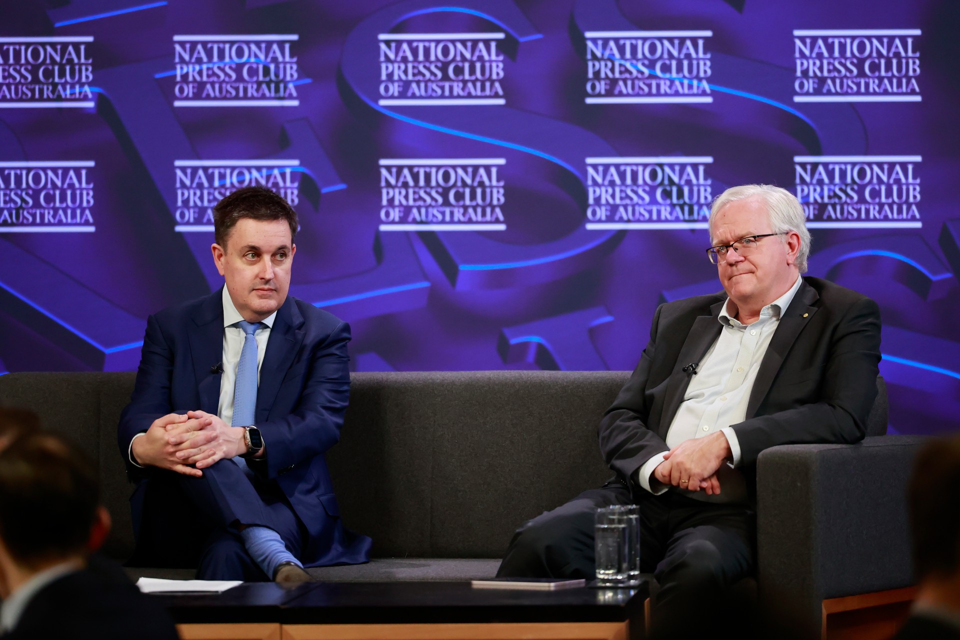 Scientia Professor Richard Holden and Professor Brian Schmidt on sit on a couch on stage at the National Press Club