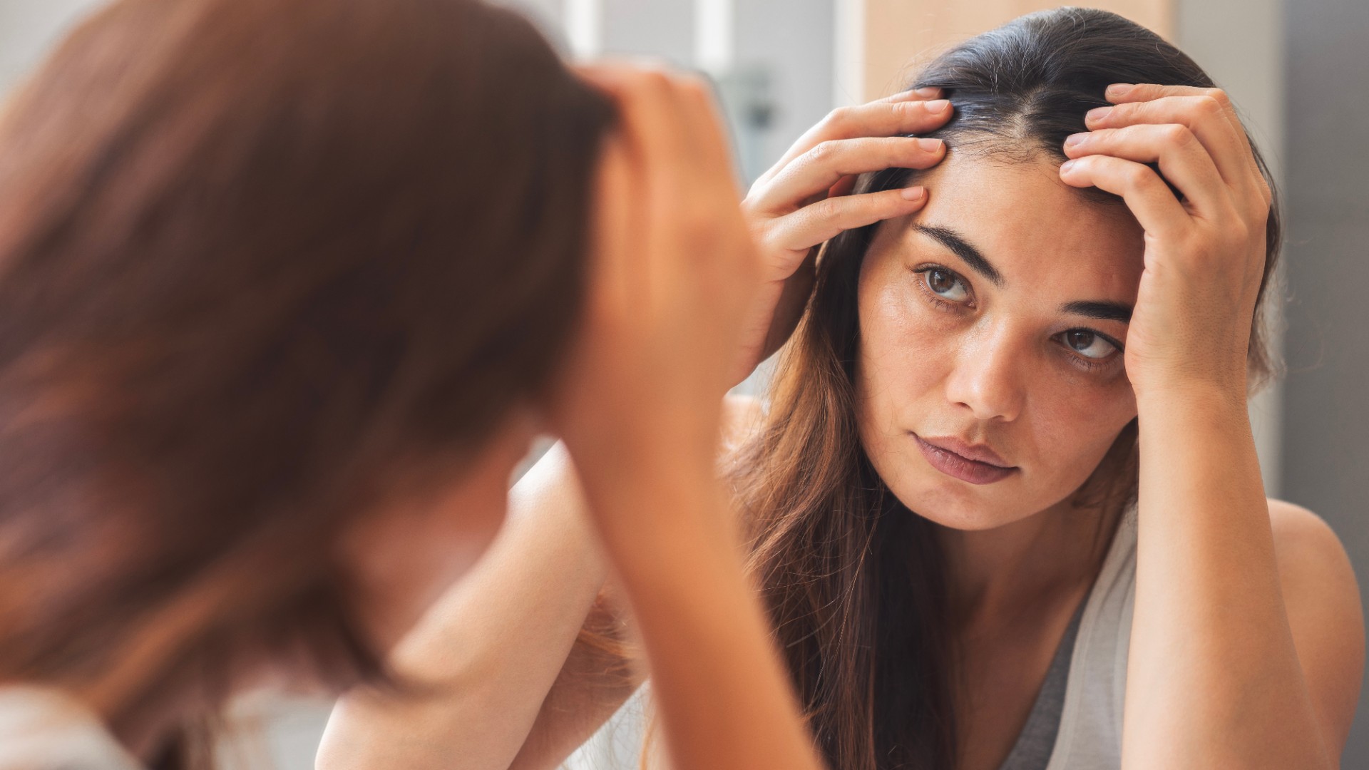 Young woman looking at herself in mirror