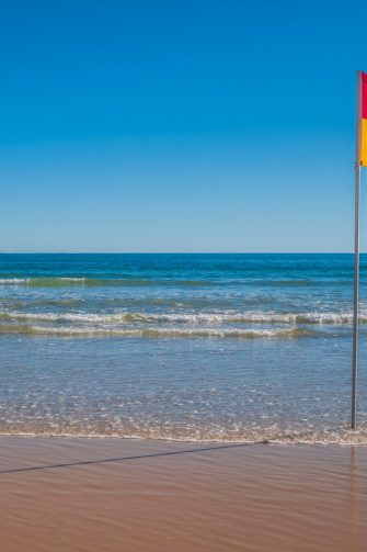 Beachscape with red and yellow flag indicating safe, patrolled beach in Australia