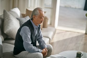 Older Asian man sitting alone at home