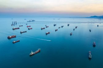 Aerial view from drone, Oil tanker ships off the coast in beautiful light sundown, professional business logistics and transportation of energy fuels.