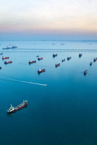 Aerial view from drone, Oil tanker ships off the coast in beautiful light sundown, professional business logistics and transportation of energy fuels.