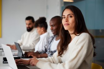 Smiling woman sitting during business meeting and looking at camera