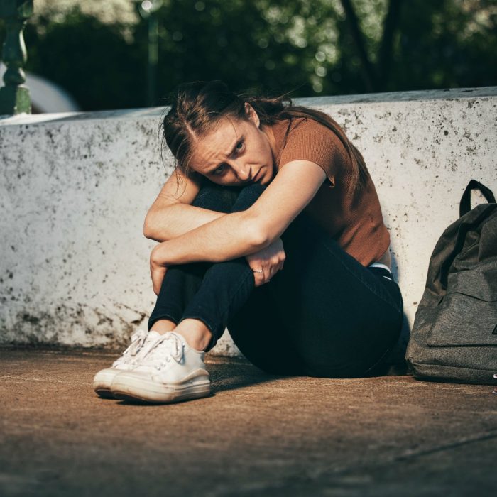 Woman, student and depression in lonely stress, anxiety or mental health problems in the outdoors. Sad and depressed female teenager in distress, loneliness or trouble at school or university.