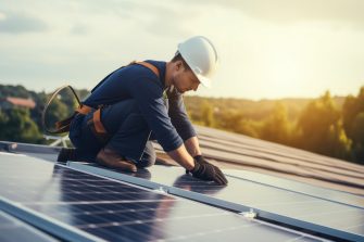 Construction industry, aerial view. An electrician in a helmet is installing a solar panel system outdoors. Engineer builds solar panel station on house roof