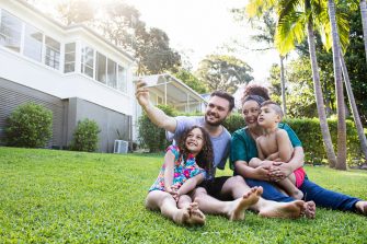 Aboriginal Family portrait with 1 parent and 2 children. They are sitting on the front porch. Everyone is happy and smiling. Could be a single mother.