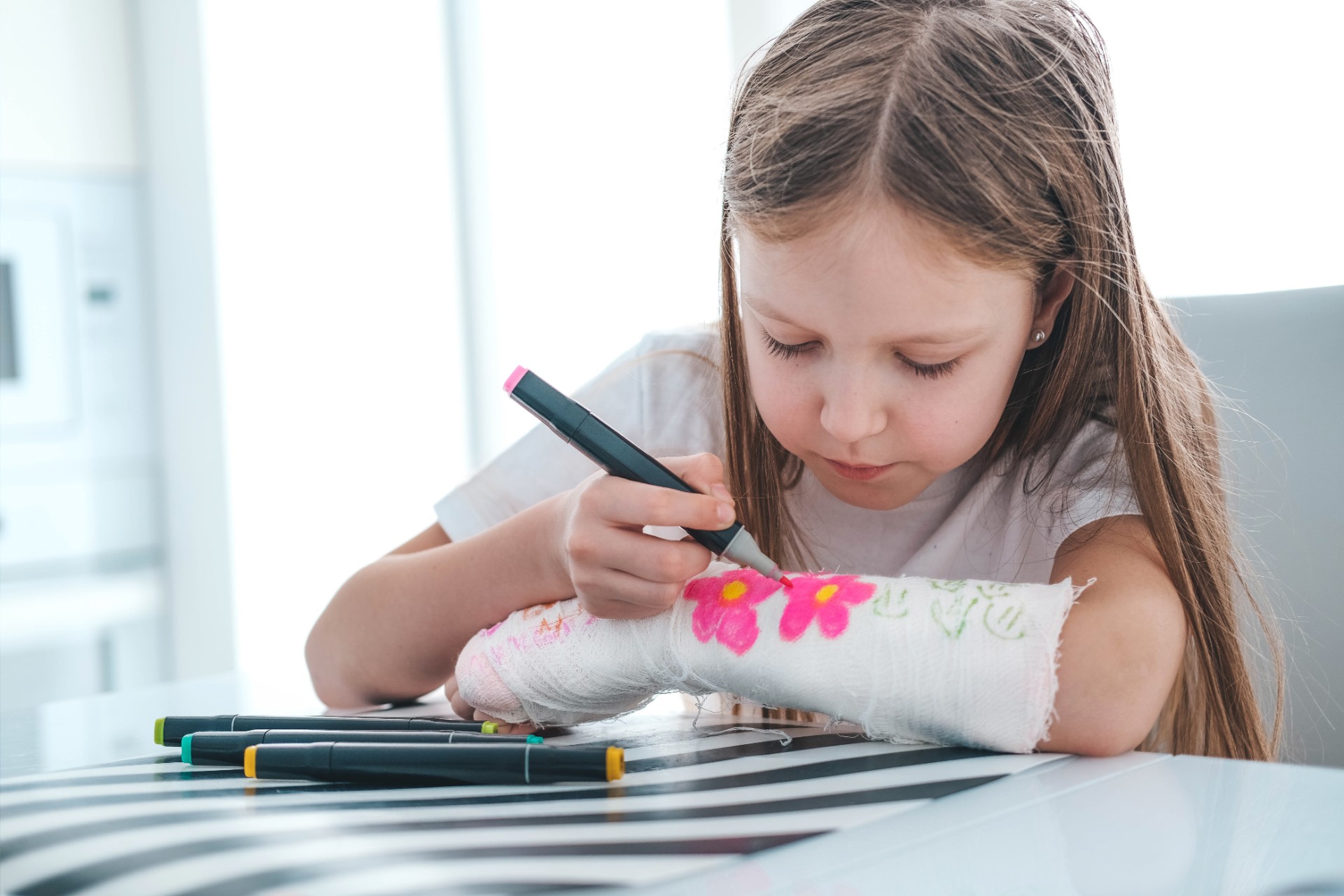 A little girl paints a cast on her arm