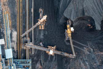 Territory of the coal terminal with coal dumps and a regenerator. loading and unloading of coal by excavators and belt conveyors. coal reserves at thermal power plants. View from above