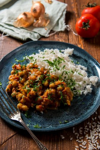 A beautifully plated meal of chickpea curry and rice on a blue plate